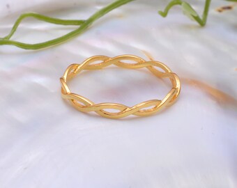 May include: A gold braided ring with a simple design. The ring is made of a smooth, shiny metal and has a delicate, intricate pattern.