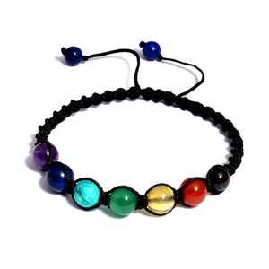 May include: A black cord bracelet with seven chakra beads. The beads are purple, blue, turquoise, green, yellow, orange, and black.