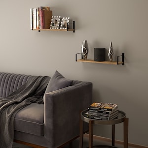 Two heavy duty shelves burnt holding a variety of books in a living room concept. These shelves are made of wood and supported by black metal brackets that attach to the wall, giving them a modern and somewhat industrial look.