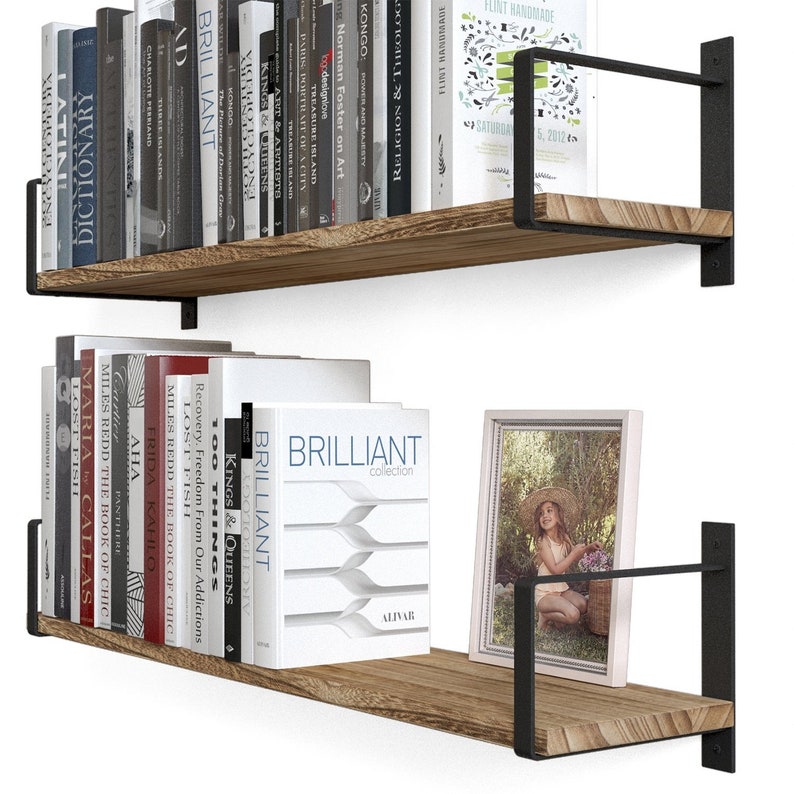 Two hanging shelves burnt holding a variety of books and picture frame of a child. These shelves are made of wood and supported by black metal brackets that attach to the wall, giving them a modern and somewhat industrial look.