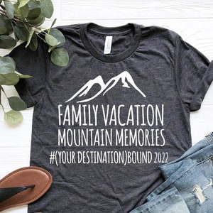 May include: A dark gray t-shirt with a white mountain graphic and the text "Family Vacation Mountain Memories #YOUR DESTINATION BOUND 2022".