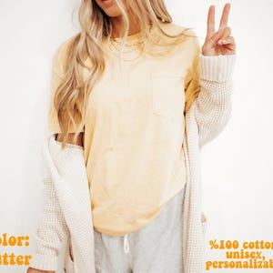 Może przedstawiać: Maślano-ż&oacute;łty t-shirt z kr&oacute;tkim rękawem i kieszenią na piersi, zestawiony z kremowym kardiganem o waflowym splocie oraz szarymi szortami ze sznurkiem. Tekst na obrazku brzmi: color: butter, %100 cotton, unisex, personalizable.