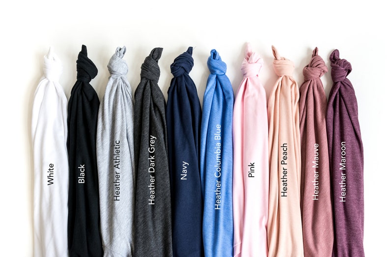 May include: A collection of folded t-shirts in various colors, including white, black, navy, and pink. Each shirt is labeled with its color name, such as "Heather Athletic" and "Heather Maroon". The shirts are displayed against a white background.