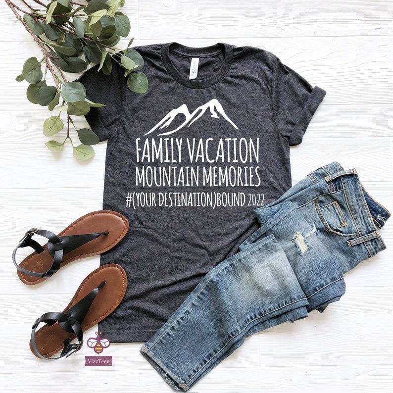 May include: A dark gray t-shirt with a white mountain graphic and the text "Family Vacation Mountain Memories #YOUR DESTINATION BOUND 2022".