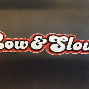 Può includere: Testo bianco su sfondo rosso con contorno nero che dice "Low & Slow".