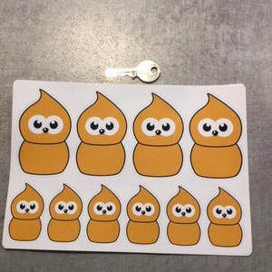 Op de afbeelding: Een vel stickers met acht oranje cartoonfiguren met zwarte ogen en witte pupillen. De figuren zijn in verschillende maten en zijn gerangschikt in twee rijen.