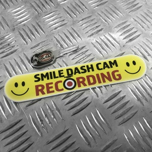 Può includere:  Adesivo per dashcam giallo e rosso con il testo "SMILE DASH CAM RECORDING" e due faccine sorridenti.