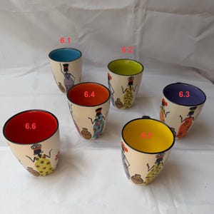 May include: Six ceramic mugs with hand-painted African-inspired designs and coloured interiors. Each mug has a different interior colour: blue, green, purple, orange, yellow, and red. The exterior is cream-coloured with a woman figure.
