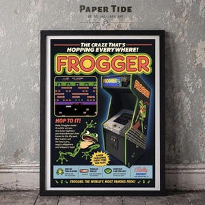 Op de afbeelding: Een ingelijste poster van het arcadespel Frogger met de titel in geel en rood, een screenshot van de gameplay, een illustratie van een groene kikker en de tekst: The Craze That's Hopping Everywhere! Hop To It! Bally Midway en Frogger: The World's Most Famous Frog.