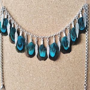 May include: A silver chain necklace with turquoise and brown feathers. The feathers are attached to the chain with silver connectors. The necklace has a hook clasp and a chain extender.
