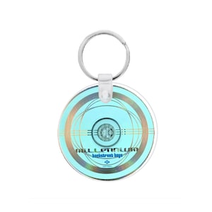 May include: A round keychain with a light blue and silver design. The keychain features the text "Millennium Backstreet Boys" in blue. The design includes concentric circles and a central circular element. A silver key ring is attached.