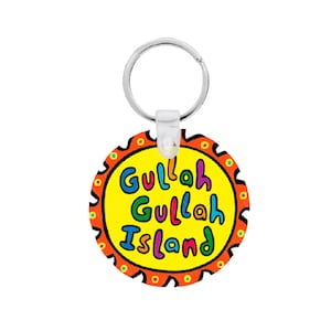Może przedstawiać: Okrągły brelok do kluczy z napisem "Gullah Gullah Island" w kolorowych literach na żółtym tle. Brelok ma srebrny kółko do kluczy i przezroczysty plastikowy element.