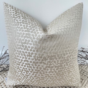 Puede incluir: Una almohada beige con un sutil estampado de leopardo. La almohada está hecha de una tela suave y texturizada.