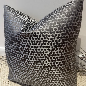 May include: A black and silver pillow with a leopard print pattern. The pillow is made of a soft, luxurious fabric and is perfect for adding a touch of style to any room.