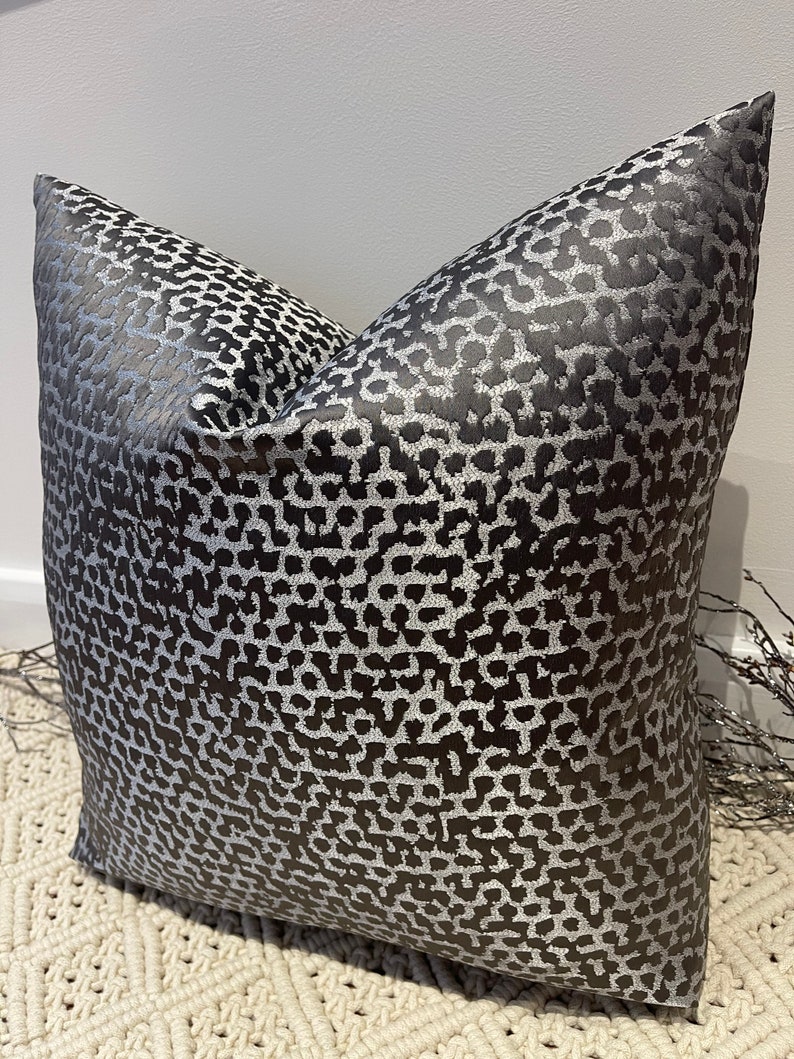May include: A black and silver pillow with a leopard print pattern. The pillow is made of a soft, luxurious fabric and is perfect for adding a touch of style to any room.