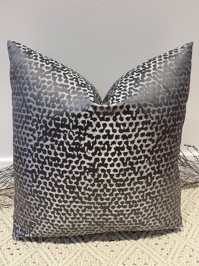 May include: A gray and silver pillow with a leopard print pattern.