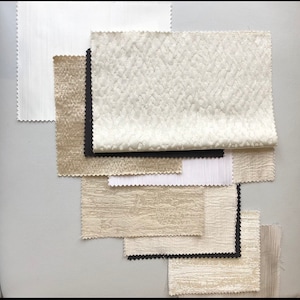 May include: A collection of fabric swatches in various shades of beige and white, with some having a textured surface.