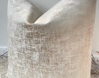 May include: A soft, cream-coloured pillow with a subtle gold shimmer and a textured, distressed pattern.