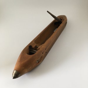 Peut inclure: Une navette en bois avec une pointe métallique et un crochet métallique. La navette est utilisée pour le tissage.