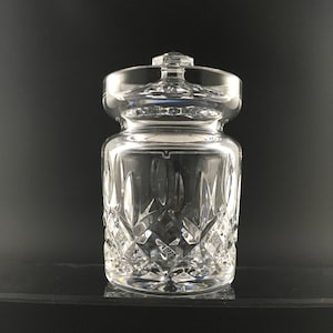 May include: A clear glass jar with a lid, featuring a cut crystal design. The jar is empty and has a round shape.