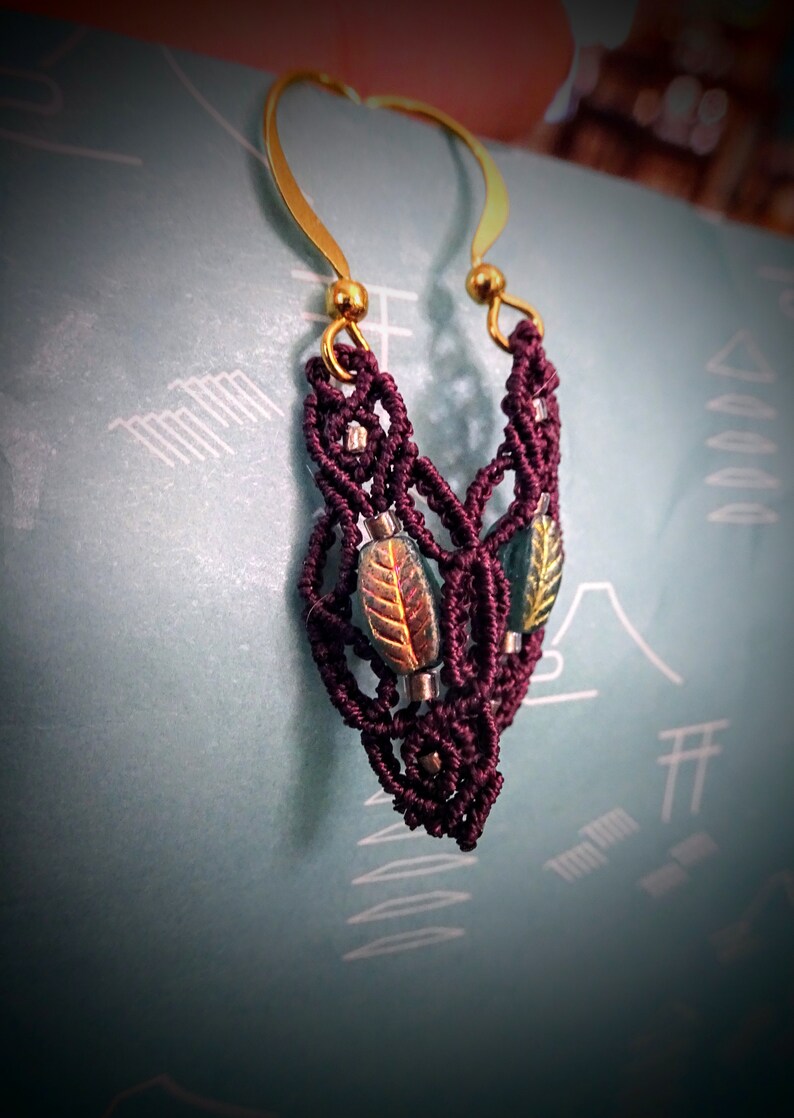 May include: Burgundy macrame earrings with gold hoops and green and gold leaf accents.