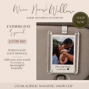 May include: Clear acrylic magnetic visor clip with a photo of a family. The photo is in a clear acrylic frame and is held by a silver clip. The text "Drive Safe Dada we love you" is printed on the photo.