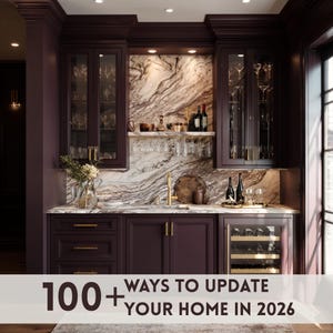 May include: A built-in home bar with dark purple cabinetry, a marble backsplash, and a wine refrigerator. The bar features glass-front cabinets, a gold faucet, and the text "100+ WAYS TO UPDATE YOUR HOME IN 2026" at the bottom.