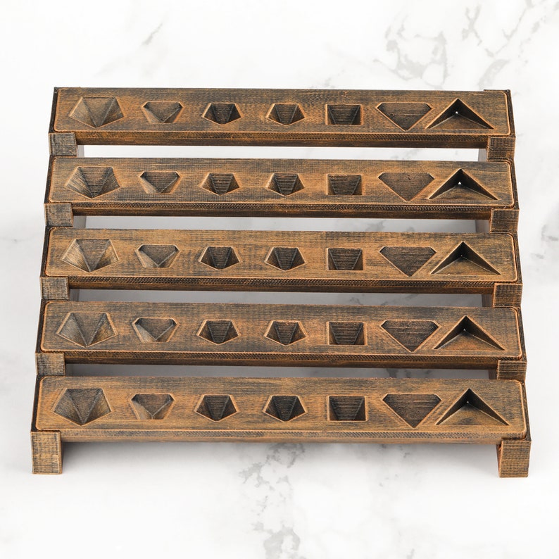 Peut inclure: Pr&eacute;sentoir en bois &agrave; plusieurs niveaux avec une finition bronze vieilli. Chaque niveau pr&eacute;sente des d&eacute;coupes g&eacute;om&eacute;triques en forme de diamants, triangles et carr&eacute;s. Le pr&eacute;sentoir est con&ccedil;u pour contenir de petits objets, tels que des bijoux ou des objets de collection.