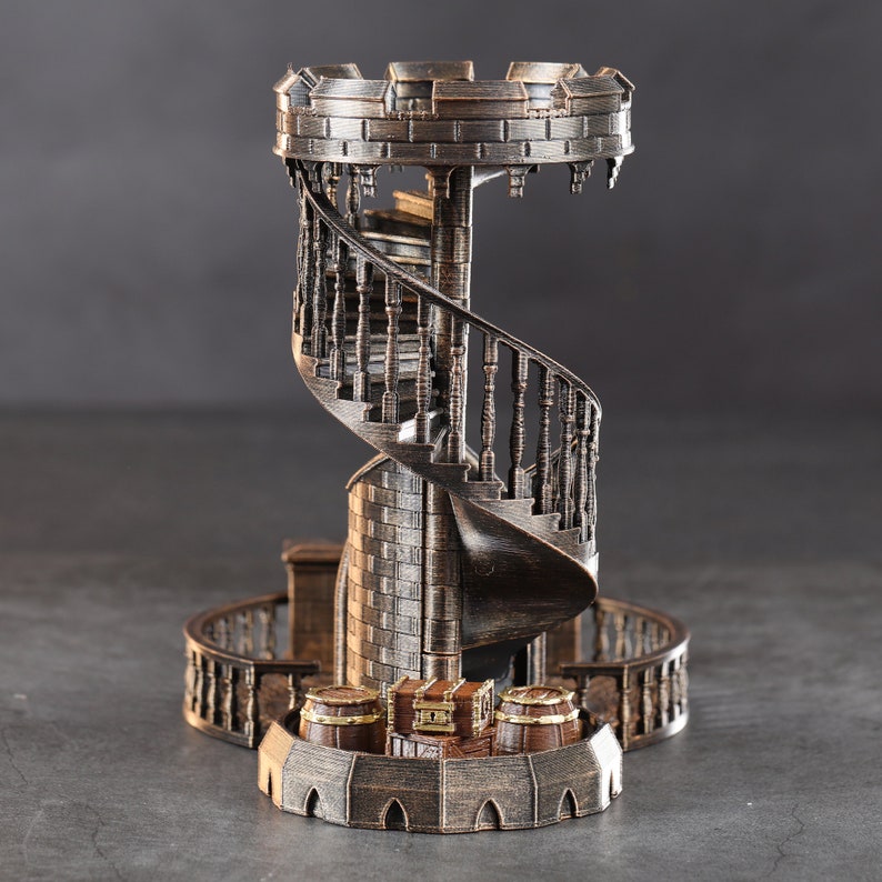 May include: A decorative metal tower with a spiral staircase and a chest at the top. The tower is made of a dark brown metal and has a rustic look. The chest is made of a lighter metal and has a gold finish.