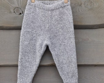May include: Gray knitted pants hanging on a gold hanger with clips. The pants are made of a soft, fuzzy material.