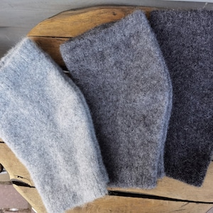 Könnte beinhalten: Drei gestrickte Armwärmer in verschiedenen Grautönen. Die Armwärmer sind aus einem weichen, flauschigen Material gefertigt und perfekt, um Ihre Arme im Winter warm zu halten.