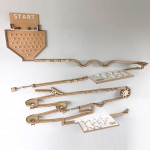 May include: A wooden marble run game with a start point labelled "START" and multiple levels of tracks. The game includes a wheel, a maze, and a funnel for the marbles to travel through.
