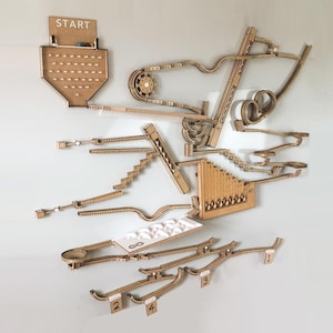 May include: A wooden marble run game with multiple levels and tracks. The game includes a start area with a wooden tray and a series of numbered tracks. The game is designed to be mounted on a wall.