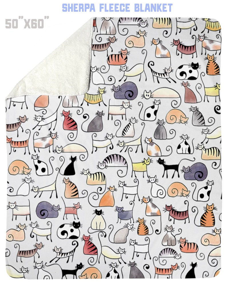 May include: A white sherpa fleece blanket with a pattern of colorful hand-drawn cats. The blanket is 50 inches by 60 inches.