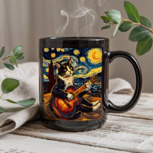 Peut inclure: Mug en céramique noire avec un chat jouant de la guitare sur un fond inspiré de "La Nuit étoilée" de Van Gogh. Le chat est noir et blanc, et la guitare est orange. La tasse a une grande anse.
