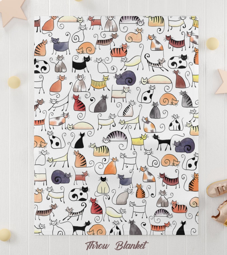 May include: White throw blanket with a repeating pattern of black, gray, orange, and yellow stylized cats. The cats are drawn in a simple, cartoon style.