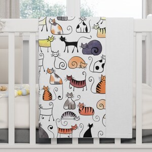 May include: White throw blanket with a colorful pattern of cats. The cats are drawn in a simple, cartoon style and are in various poses. The blanket has the words "Throw Blanket" printed on the bottom.