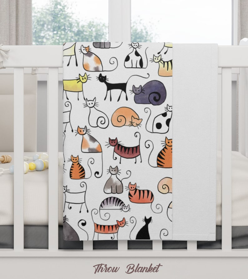 May include: White throw blanket with a colorful pattern of cats. The cats are drawn in a simple, cartoon style and are in various poses. The blanket has the words "Throw Blanket" printed on the bottom.