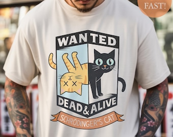 May include: Cream-colored t-shirt featuring a graphic of two cats, one orange and one black, within a "WANTED" poster design. The text reads "DEAD & ALIVE" and "Schrödinger's Cat". The shirt has a crew neck and short sleeves.