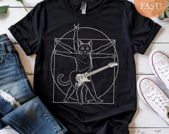 Puede incluir: Camiseta negra con un gráfico blanco de un gato tocando la guitarra, inspirado en el Hombre de Vitruvio de Leonardo da Vinci. El gato se representa con múltiples brazos y un gesto de la mano rock and roll.