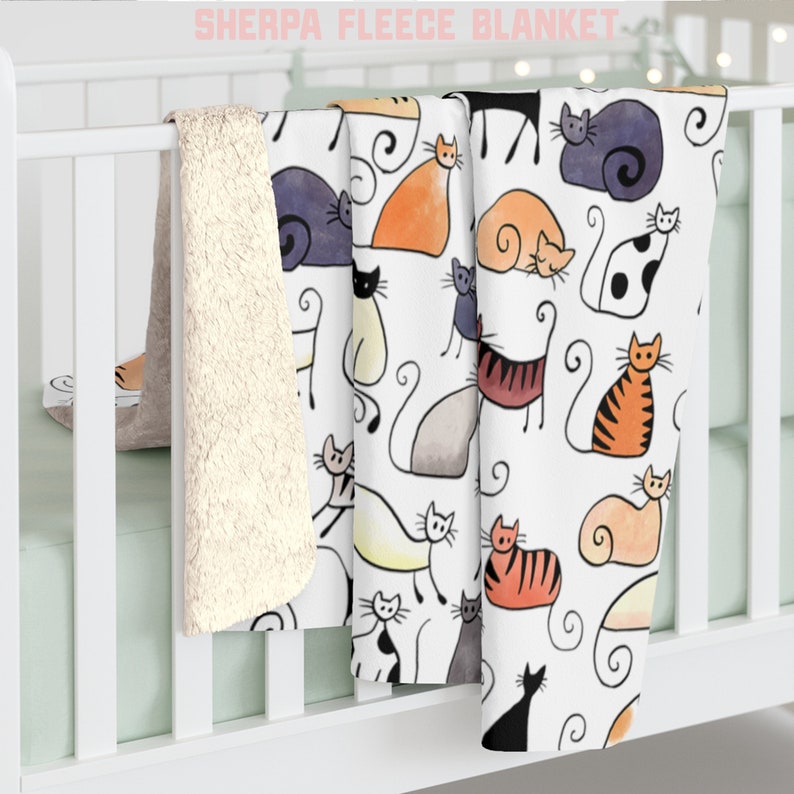 May include: A white sherpa fleece blanket with a colorful cat print. The blanket features a variety of cats in different poses and colors, including orange, black, white, and gray. The blanket is soft and cozy, perfect for snuggling up on the couch or in bed.