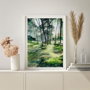 May include: A watercolor painting of a forest scene with tall trees and green foliage. The painting is framed in a white frame and is hanging on a white wall.