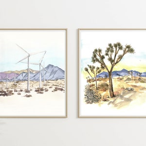 May include: Two framed watercolor paintings. The first painting depicts a desert landscape with wind turbines and mountains in the background. The second painting shows a Joshua Tree in the foreground with a desert landscape in the background.