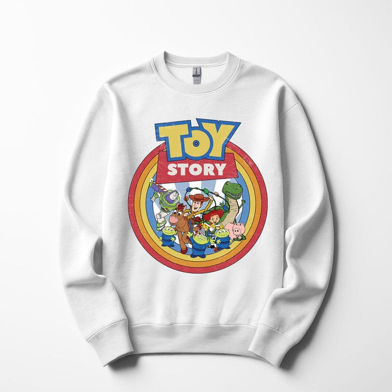 Puede incluir: Sudadera blanca de cuello redondo con un gr&aacute;fico colorido de personajes de la pel&iacute;cula animada "Toy Story". El dise&ntilde;o incluye el logotipo de la pel&iacute;cula en azul y amarillo, rodeado por un c&iacute;rculo de colores del arco&iacute;ris e im&aacute;genes de Woody, Buzz Lightyear y otros personajes.