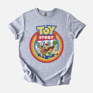 Puede incluir: Camiseta gris jaspeado con un dise&ntilde;o colorido de la pel&iacute;cula "Toy Story". El dise&ntilde;o circular incluye el t&iacute;tulo y personajes como Buzz Lightyear y Woody. La camiseta de manga corta y cuello redondo es ideal para fans.