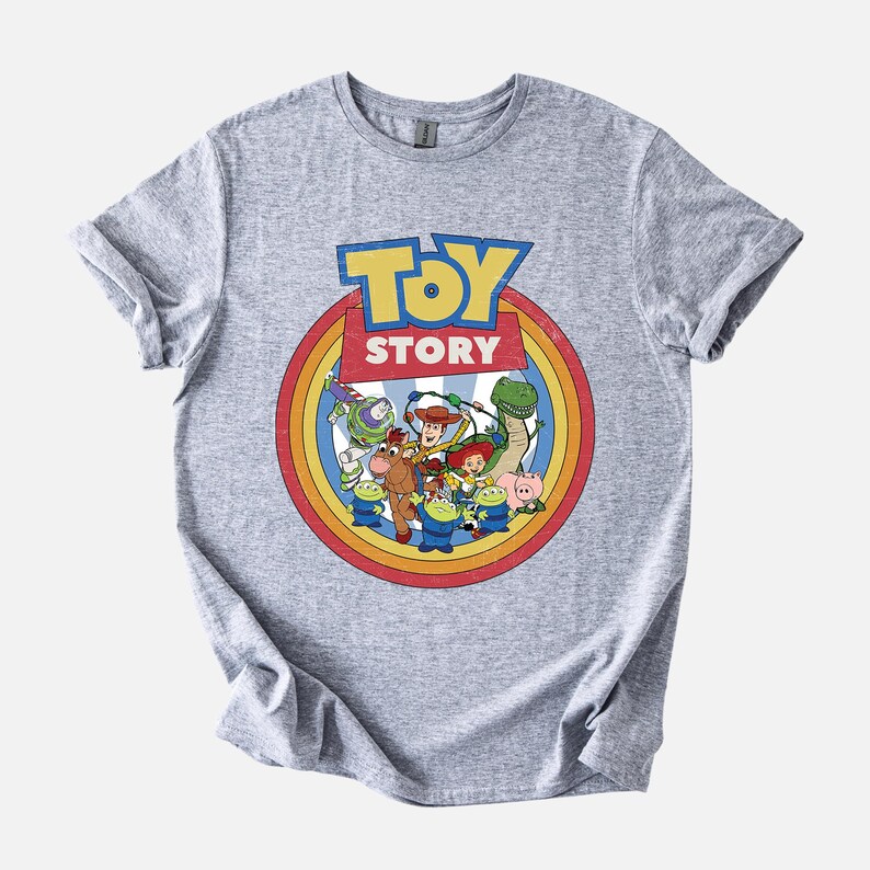 Puede incluir: Camiseta gris jaspeado con un dise&ntilde;o colorido de la pel&iacute;cula "Toy Story". El dise&ntilde;o circular incluye el t&iacute;tulo y personajes como Buzz Lightyear y Woody. La camiseta de manga corta y cuello redondo es ideal para fans.
