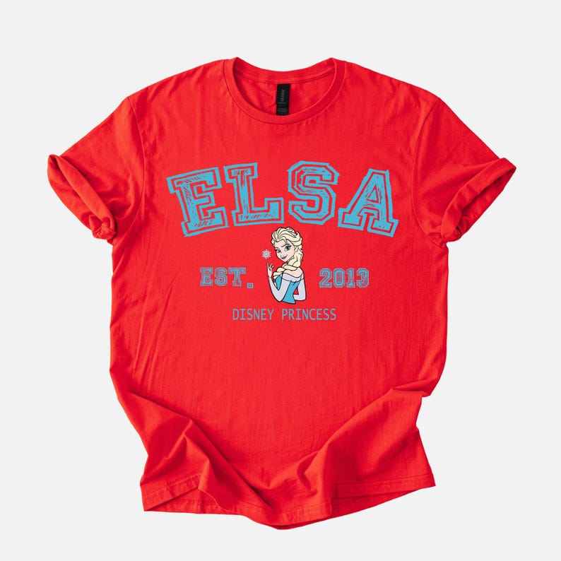 K&ouml;nnte beinhalten: Rotes T-Shirt mit dem Namen "ELSA" in hellblauen Blockbuchstaben. Darunter ein Bild von Elsa aus Disneys Frozen, mit dem Text "EST. 2013" und "DISNEY PRINCESS" in Hellblau.