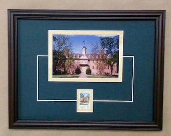 May include: Framed print featuring a building with a white steeple, trees, and a small stamp. The frame is dark brown, and the matting is teal with white accents. The image is displayed on a neutral-colored background.