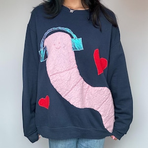 May include: A navy blue sweatshirt with a pink worm wearing blue headphones and two red hearts.