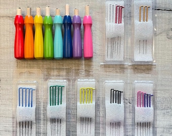 May include: A collection of eight wooden needle felting tools with colorful handles in red, orange, yellow, green, light blue, dark blue, purple, and pink, alongside five clear plastic blister packs containing sets of assorted metal felting needles.